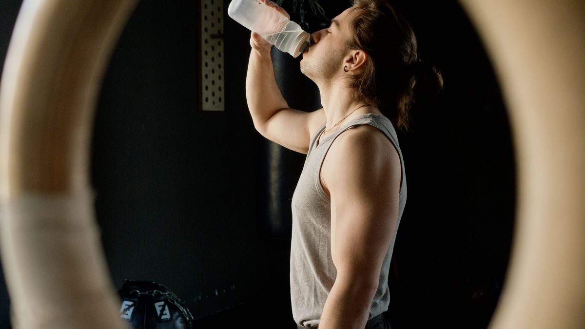 Joven deportista tomando su bebida de recuperación en el gimnasio